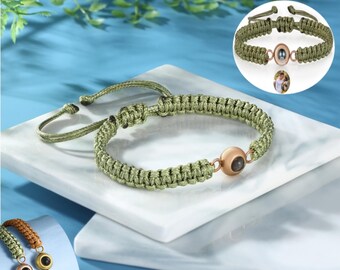 Könnte beinhalten: Olivgrünes Makramee-Armband mit einer bronzefarbenen Mittelperle. Das Armband wird auf einer weißen Oberfläche mit blauem Hintergrund präsentiert. Zusätzliche Armbänder sind unten links und eine Nahaufnahme oben rechts abgebildet.