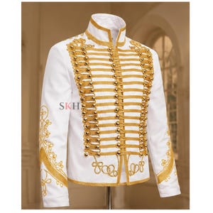 May include: A white jacket featuring gold embroidery and gold-toned buttons arranged in horizontal rows across the front. The collar is high and structured, and the sleeves are decorated with gold patterns. The text SKH is visible on the chest.