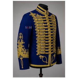 May include: A royal blue military-style jacket featuring intricate gold embroidery and horizontal gold braided cord detailing across the front. The garment includes a high collar, long sleeves with matching gold embellishments, and the letters SKH.