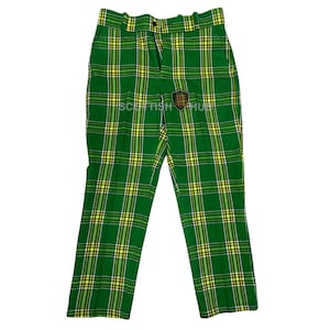 May include: Green plaid pants with yellow and white accents. The pants have a button closure and a small emblem. The text "SCOTTISH HUB" is visible on the pants. These pants are a traditional style.