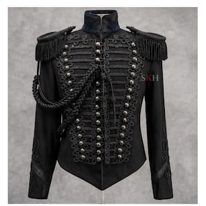 May include: A black military-style jacket featuring intricate black cord braiding, silver-toned buttons, and shoulder epaulets with fringe. The garment includes a high collar, long sleeves with decorative embroidery, and the letters SKH in red.