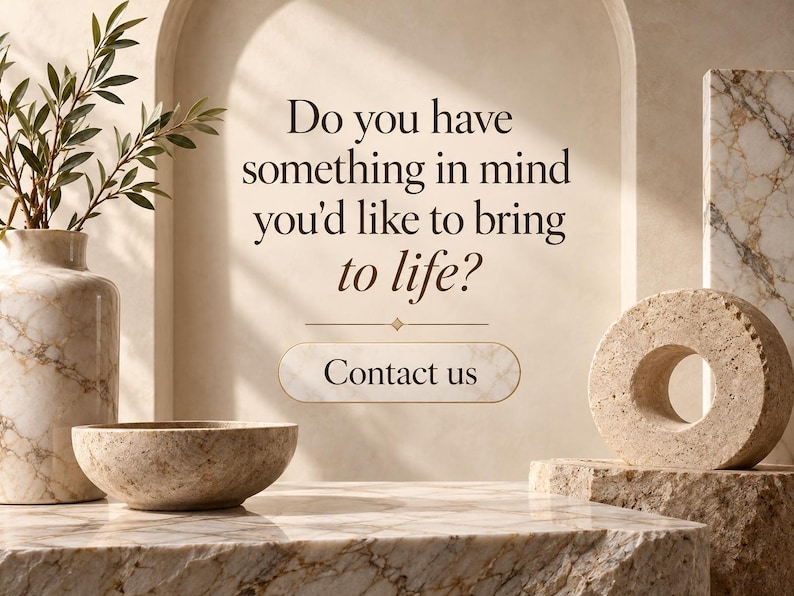 May include: A marble vase with green foliage, a marble bowl, and a circular stone sculpture on a marble surface. The text reads: Do you have something in mind you'd like to bring to life? Contact us. The background features a beige arched wall.