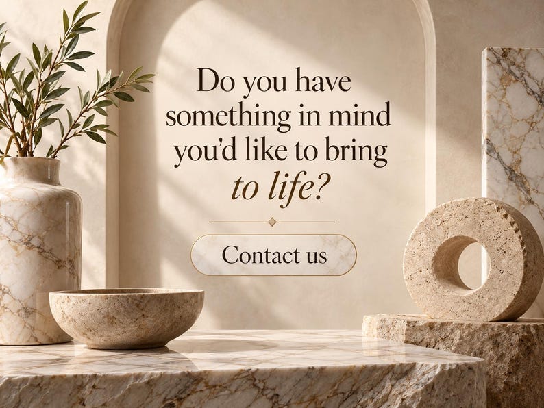 May include: A marble vase with green foliage, a marble bowl, and a circular stone sculpture on a marble surface. The text reads: Do you have something in mind you'd like to bring to life? Contact us. The background features a beige arched wall.