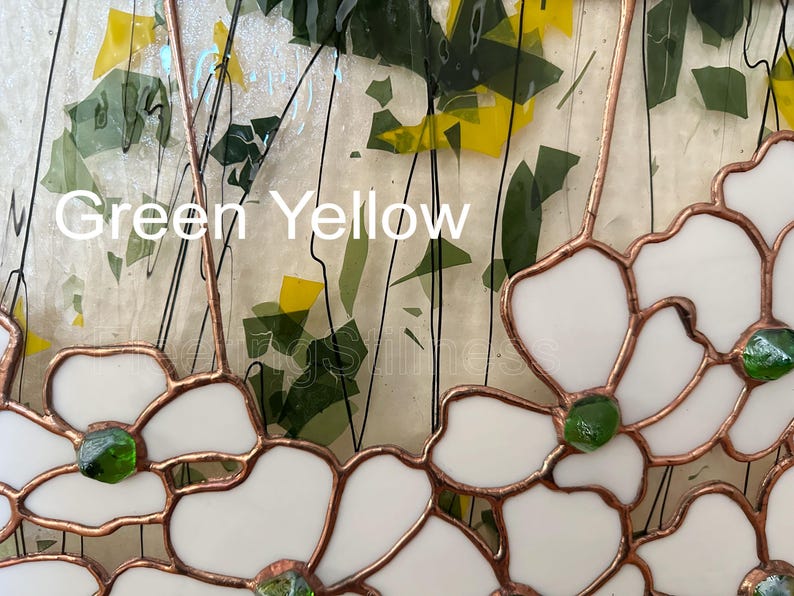 May include: A stained glass panel featuring white flower shapes outlined in copper foil, accented with small green glass centers. The background consists of clear glass with scattered green and yellow glass shards and black wire lines. Text reads Green Yellow.