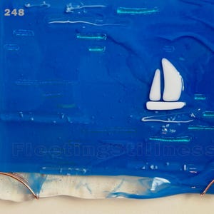 May include: A rectangular fused glass art piece featuring a deep blue background with a white sailboat silhouette. The text 248 appears in the top left corner, and the text FleetingStillness is centered near the bottom. Copper wire accents the base.