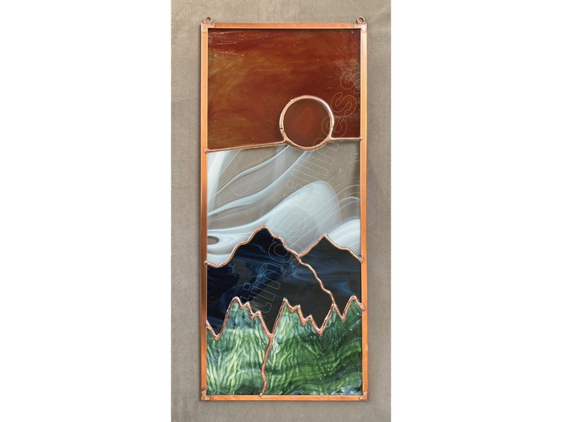 May include: A stained glass window depicting a sunset over mountains. The sky is a gradient of orange, white, and blue. The mountains are green and black. The sun is a circle of orange glass.