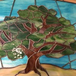 May include: A stained glass window depicting a tree with green leaves and a brown trunk against a blue sky background.