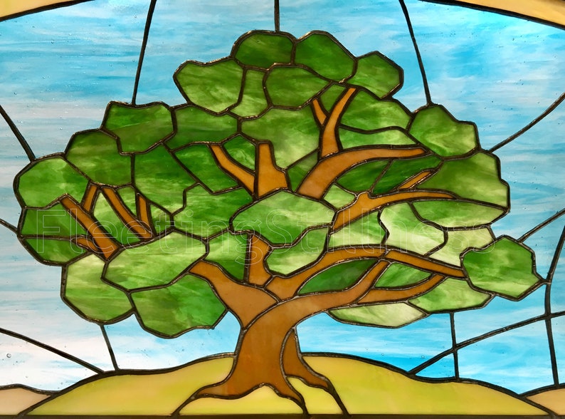 May include: A stained glass window depicting a large green tree with brown branches against a blue sky background.