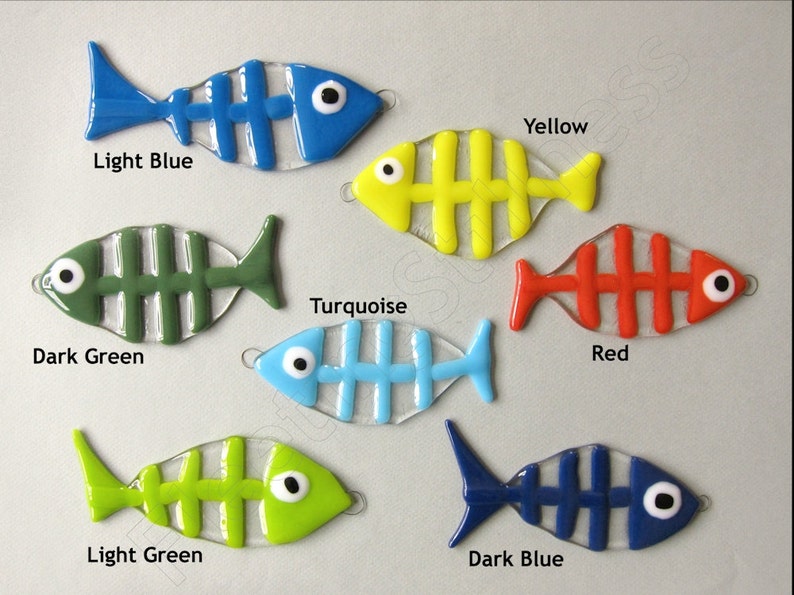 K&ouml;nnte beinhalten: Sieben gl&auml;serne Fisch-Ornamente mit einem Skelett-Design. Die Fische sind in den Farben hellblau, dunkelgr&uuml;n, t&uuml;rkis, rot, hellgr&uuml;n und dunkelblau. Die Fische sind alle nach rechts im Bild ausgerichtet.