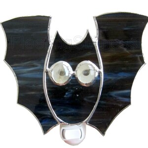 May include: A stained glass bat nightlight with a black and blue glass body and white eyes. The nightlight has a standard plug-in socket.