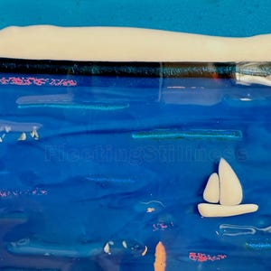May include: A fused glass art piece featuring a deep blue ocean scene with a white sailboat, a white shoreline, and the text 249 and FleetingStillness. The composition includes horizontal blue glass layers, small white accents, and pinkish details.