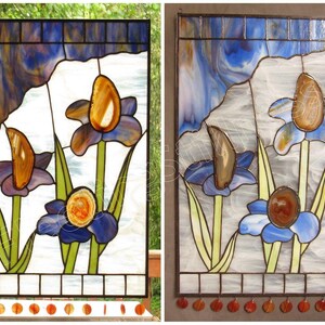 May include: A stained glass window depicting three blue iris flowers with agate accents. The flowers are set against a white background with a blue and white swirled glass sky.