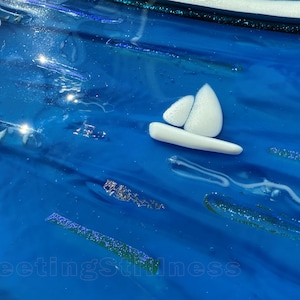May include: A glossy blue glass surface featuring a small white sailboat icon, iridescent glitter accents, and the text 249 in the upper left corner and FleetingStillness at the bottom. The surface has a wavy, fluid texture with light reflections.