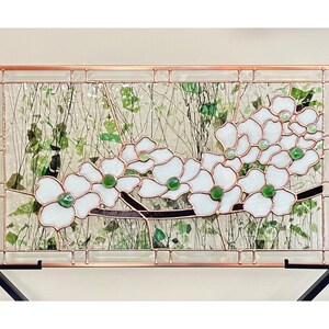 May include: A rectangular stained glass panel featuring white dogwood flowers with green glass centers and dark brown branches. The design is framed in copper metal with a clear textured glass background containing green leaf-like glass shards.