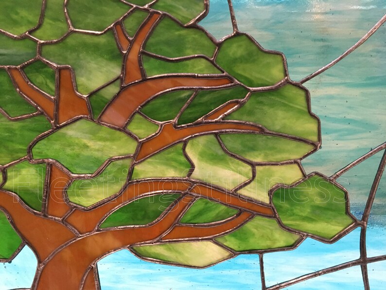 May include: A stained glass window depicting a tree with brown branches and green leaves against a blue sky background.
