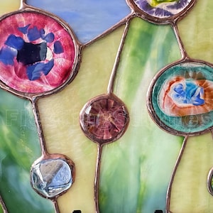 K&ouml;nnte beinhalten: Ein Buntglasfenster mit kreisf&ouml;rmigen Glaselementen in Rosa, T&uuml;rkis, Violett und Gr&uuml;n, die durch kupferfarbene Metalll&ouml;tlinien verbunden sind. Das Design umfasst strukturierte Glasst&uuml;cke mit wirbelnden Mustern und durchscheinenden gr&uuml;nen Hintergr&uuml;nden.