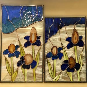 May include: Two stained glass panels depicting blue flowers with brown agate centers. The flowers are set against a background of yellow and white, with a blue sky at the top of the panels.