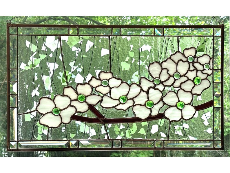 May include: A rectangular stained glass panel featuring white dogwood flowers with bright green glass centers. The flowers are arranged on a dark brown branch against a background of clear, textured glass with scattered green glass shards.