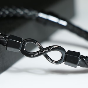Puede incluir: Pulsera de cuero negro con un símbolo de infinito plateado grabado con el texto "Ethan 27°56'46.9"N 82°46'22.8"W Charlotte".