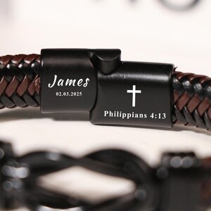 May include: Braided leather bracelet with a black clasp. The clasp is engraved with the name "James" and the date "02.03.2025". A cross and the text "Philippians 4:13" are also visible on the clasp. The bracelet features brown and black leather.
