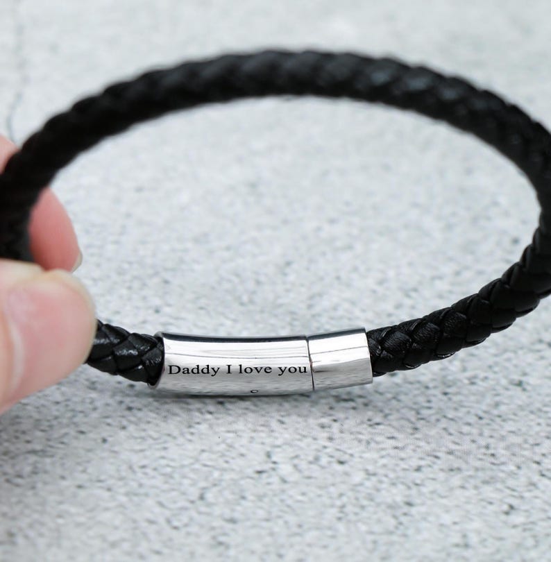 Puede incluir: Pulsera de cuero negro con cierre plateado grabado con las palabras "Daddy I love you".
