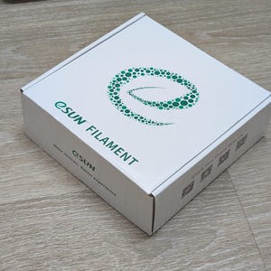 May include: A white cardboard box with the text "eSUN FILAMENT" in green and black. The box features a green dotted design and the tagline "More choices, Better experience."