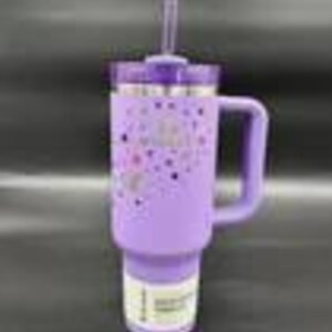 Pu&ograve; includere: Un bicchiere termico lavanda con manico e cannuccia. Il bicchiere ha un coperchio viola e un bordo argentato. Il corpo del bicchiere &egrave; decorato con un motivo di cuori e stelle rosa e viola. Il bicchiere &egrave; progettato per bevande fredde.