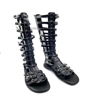 May include: A pair of black leather gladiator sandals. These knee-high sandals feature multiple straps and buckles, and an open toe design. The sandals are made of leather and are designed with multiple straps and buckles for a secure fit.