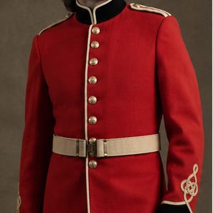 May include: A bright red military-style tunic featuring a high black collar, gold-toned buttons, and cream-colored piping along the front closure and shoulders. The sleeves have black cuffs with gold braided embroidery and a beige waist belt.