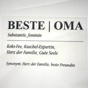 Könnte beinhalten: Eine weiße Karte mit schwarzem Text, der "BESTE | OMA" mit deutschen Wörtern und Phrasen lautet. Die Karte enthält die Definition von "OMA" und Synonyme. Gänseblümchen und eine Tasse Kaffee sind im Hintergrund.