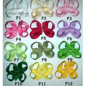 May include: Twelve different colored hair bows, each with a different color and design. The bows are arranged in four rows of three, with the colors ranging from white to green to yellow. The bows are labeled F1 through F12.