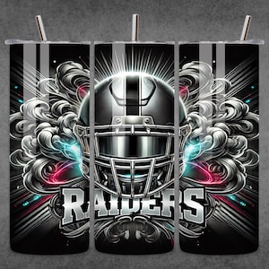 Könnte beinhalten: Ein schwarzer und silberner Becher mit einer Grafik eines Footballhelms und dem Wort "RAIDERS" in einer stilisierten Schriftart. Der Helm ist von silbernen und grauen rauchähnlichen Designs umgeben.
