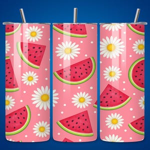 Puede incluir: Juego de tres vasos de acero inoxidable con fondo rosa. Los vasos están decorados con un estampado de rodajas de sandía, margaritas blancas y lunares blancos. Cada vaso tiene una pajita plateada.