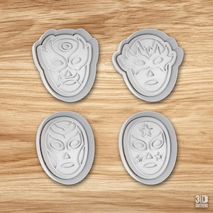 May include: Four white plastic cookie cutters shaped like luchador masks. Each cutter features a distinct mask design with cutouts for eyes, noses, and mouths. One mask includes star details. The text 3D CUTTERS is visible in the bottom right corner.
