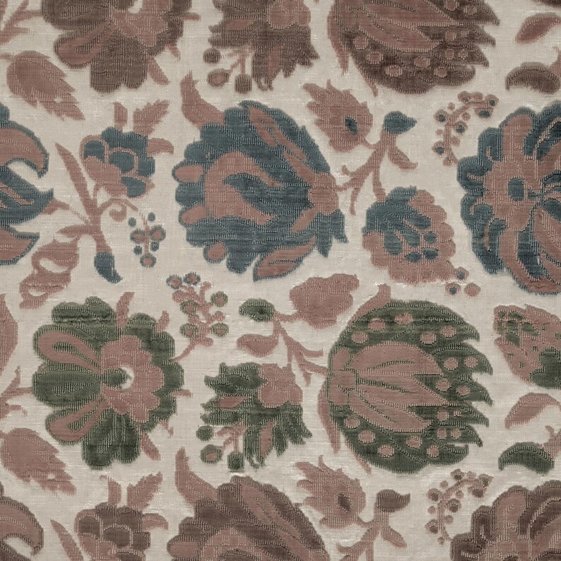 May include: Close-up of a fabric with a repeating floral pattern. The design features large, stylized flowers in shades of brown, green, and blue against a cream-colored background. The fabric has a textured appearance.