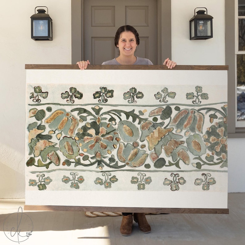 May include: A large, rectangular artwork with a detailed floral design in shades of green, blue, and tan, set against a white background. The artwork is framed in a dark wood. The overall aesthetic is reminiscent of vintage botanical illustrations.