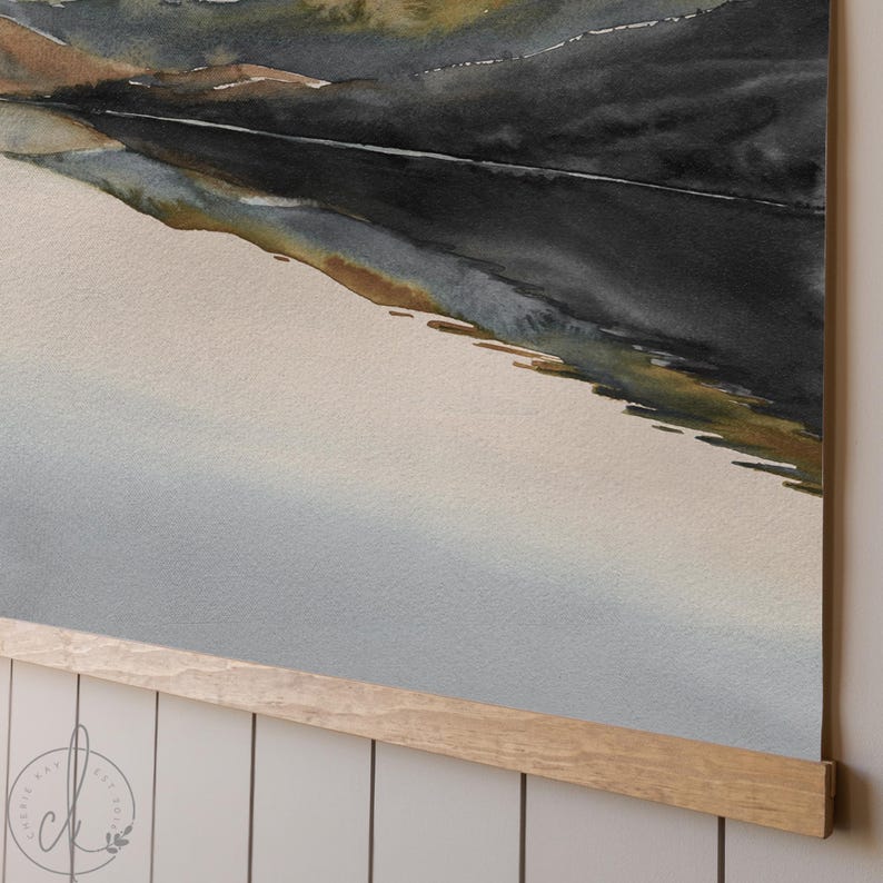 May include: Watercolor landscape art print featuring a mountain range in shades of black, brown, and green. The artwork is displayed on a light-colored paper and is held by a natural wood frame. The print is a decorative piece for home decor.