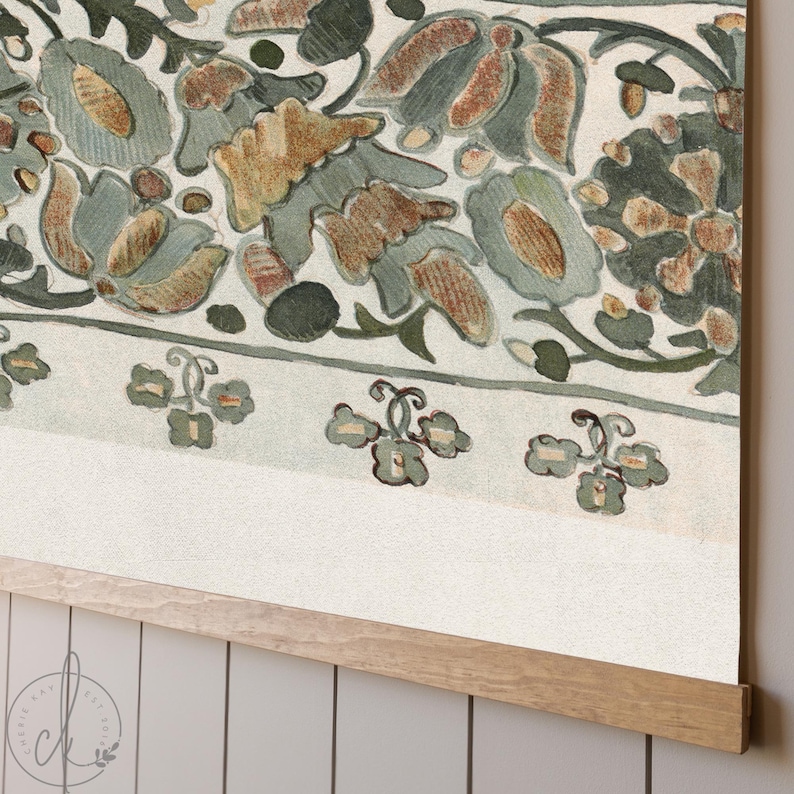 May include: A close-up of a floral print wall hanging. The design features muted tones of green, brown, and beige. The print is mounted on a wooden frame, adding a natural touch to the artwork. The floral pattern is detailed and intricate.