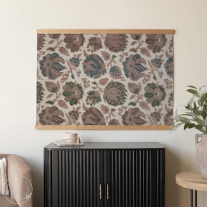 May include: Floral print wall art with a wooden frame. The artwork features a repeating pattern of stylized flowers in shades of brown, green, and blue on a cream background. The wooden frame adds a natural touch to the piece.