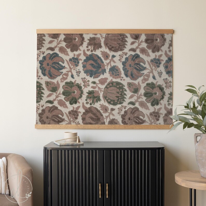 May include: Floral print wall art with a wooden frame. The artwork features a repeating pattern of stylized flowers in shades of brown, green, and blue on a cream background. The wooden frame adds a natural touch to the piece.