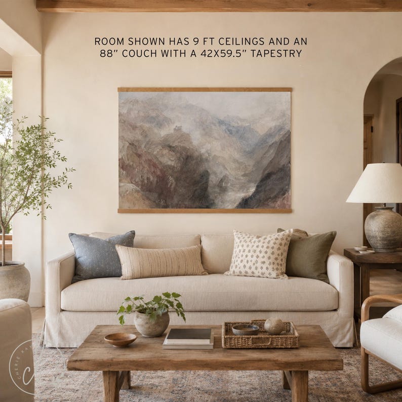 May include: A landscape wall tapestry in a wooden frame featuring a muted mountain scene, displayed above a beige sofa. Text above reads: ROOM SHOWN HAS 9 FT CEILINGS AND AN 88" COUCH WITH A 42X59.5" TAPESTRY.