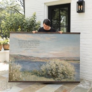 May include: A large landscape print with a wooden frame. The artwork depicts a serene waterscape with text that reads, "For I know the plans I have for you...plans to give you hope and a future." The color palette includes blues, greens, and browns.