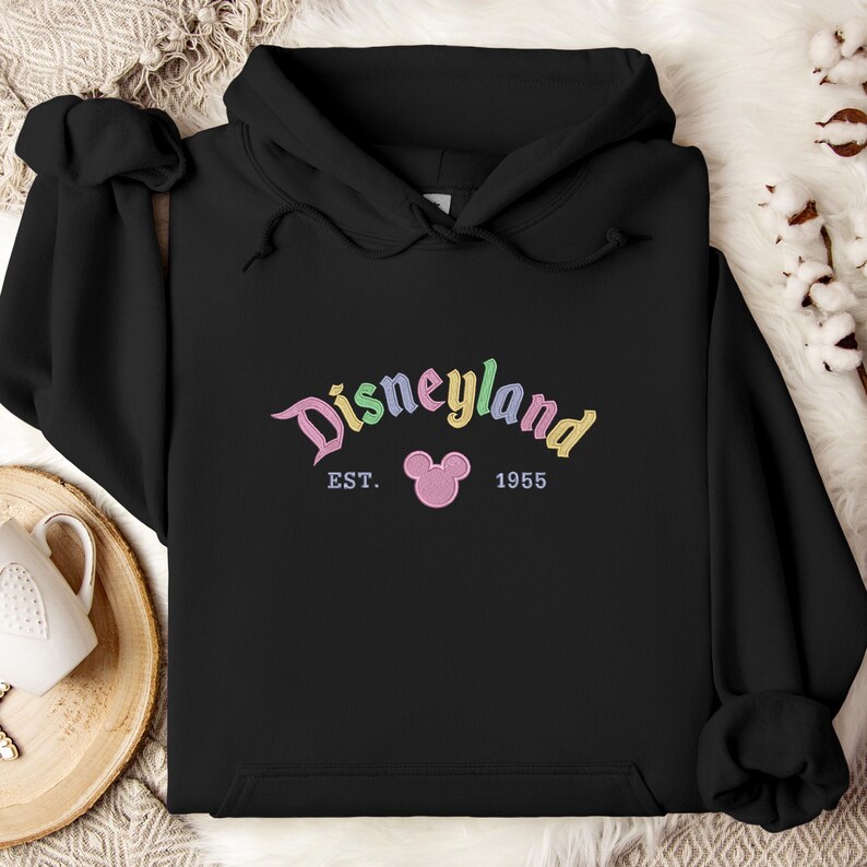 A black hoodie with the text "Disneyland EST. 1955" printed on it, along with a Mickey Mouse logo.