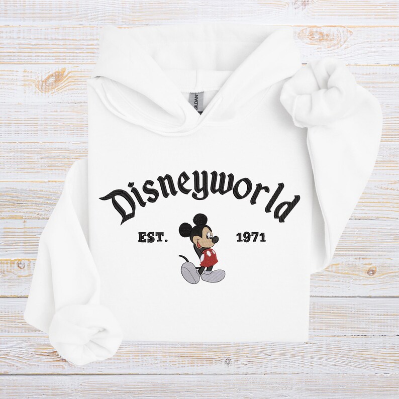 A white hoodie with the text "Disneyworld EST. 1971" and an illustration of Mickey Mouse.