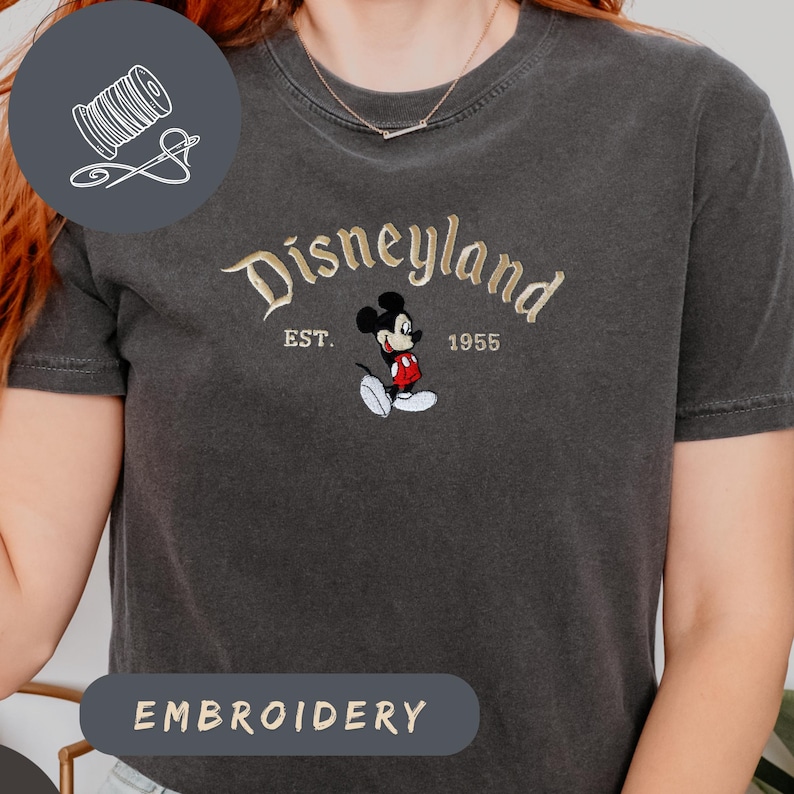 A person wearing a gray t-shirt with a Mickey Mouse embroidered on it, along with the text "Disneyland EST. 1955".
