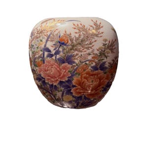 以下が含まれることがあります： クリーム色の背景に、装飾的なセラミック花瓶。ピンク、オレンジ、青の花柄のデザインが施されています。花は精巧に描かれており、視覚的に魅力的な作品です。