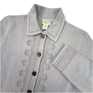 May include: A light blue Pendleton jacket with a collared neckline and long sleeves. The jacket features decorative embroidery along the front, collar, and cuffs, and is fastened with brown buttons. The Pendleton label is visible.