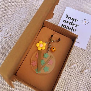 Llavero acrílico personalizado con inicial. Llavero personalizado con dije de campana y flor. Llavero personalizado con letra y colores personalizados, campana y flor.