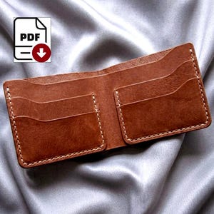 Może przedstawiać: Otwarty brązowy skórzany portfel z wieloma przegródkami na karty i białymi przeszyciami. Portfel jest pokazany otwarty, ukazując wewnętrzne przegródki. Na zdjęciu znajduje się również ikona pobierania PDF.