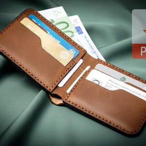 Op de afbeelding: Open bruine leren portemonnee met meerdere kaartsleuven, met creditcards en contant geld. De portemonnee is gestikt met een contrasterende draad. Een PDF-pictogram staat in de rechterbovenhoek.